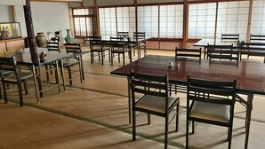 Une pièce de style japonais traditionnel, avec un sol recouvert de tatamis, des tables et des chaises en bois.