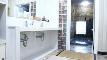 A bathroom with a white vanity, a mirror, and a shower area with a tiled floor.