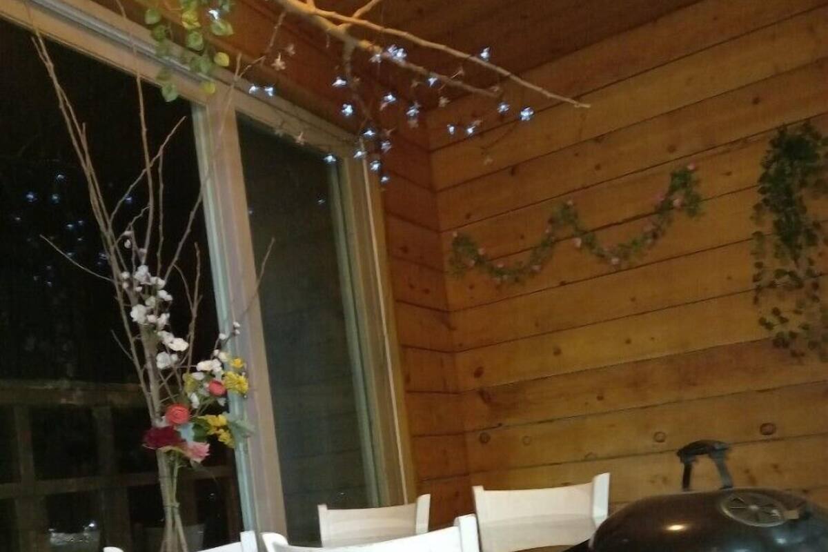A wooden interior with a dining area featuring two white chairs, a table, and a barbecue grill.
