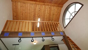 Un intérieur en bois avec un balcon, une fenêtre et un luminaire au plafond.