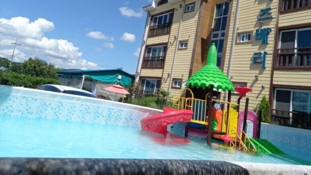 Un hôtel doté d’une piscine, d’un espace de jeux pour enfants et d’un bâtiment à plusieurs étages avec des balcons.