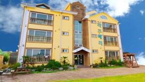 Un hôtel à plusieurs étages, avec une façade jaune, des balcons et un ciel dégagé.