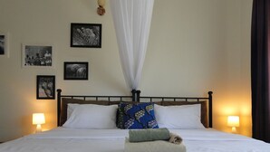 A neatly made bed with white linens, a blue patterned pillow, and a small towel on the side. There are two wall-mounted lamps on either side of the bed.