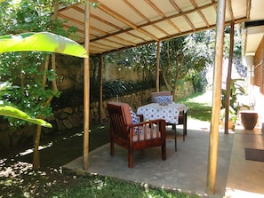 An outdoor patio with a covered seating area, stone wall, and potted plants. - Carpe Diem (Entebbe)