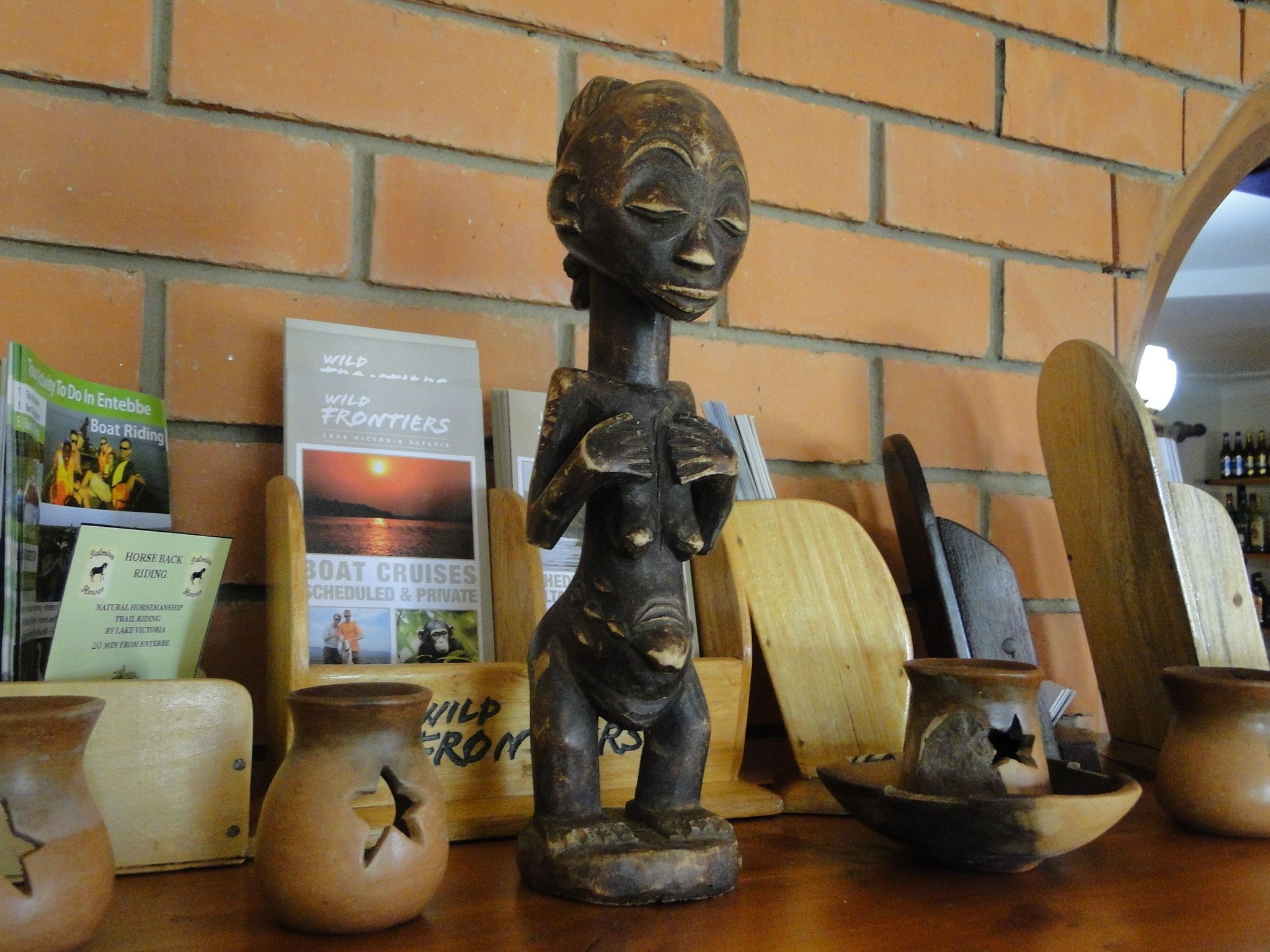 Un décor rustique avec un mur en briques, une chaise en bois et divers objets en céramique.