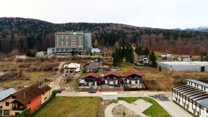 A hotel with multiple buildings, a parking area, and a hilly forested background. - Apartment Sofia (Sinaia)