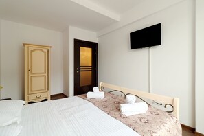 A hotel room with a bed, a wardrobe, a television, and a door. - Apartment Sofia (Sinaia)