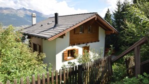 A chalet with a sloped roof, wooden exterior, and a wooden fence in front. - Chalet Joshua (Heremence)