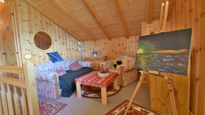 A cozy wooden cabin interior with a bed, two sofas, a small table, and a painting on the wall. - Chalet Joshua (Heremence)