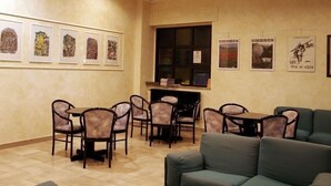 Une pièce avec un canapé vert, des chaises de salle à manger, une table et des œuvres d’art encadrées accrochées aux murs.