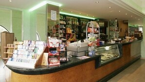 Un espace d’accueil d’hôtel avec un comptoir où sont exposés divers articles, une vitrine et des étagères remplies de produits.