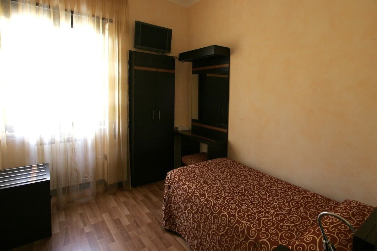 Un dormitorio con cama, armario, televisor y radiador.