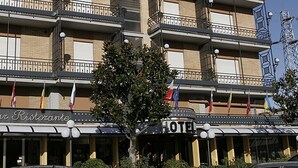 Un immeuble à plusieurs étages doté de balcons, un restaurant appelé « Bar Ristorante » situé au rez-de-chaussée, et une enseigne bien visible indiquant « HÔTEL ».