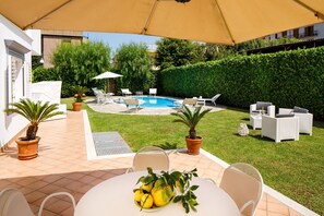A patio area with a pool, outdoor furniture, and potted plants.