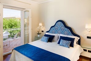 A bedroom with a bed, a balcony, and a view of greenery.