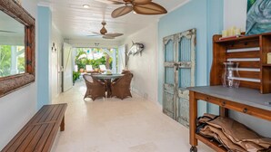 A hallway with a dining area, wooden furniture, ceiling fans, and a rustic door. - Beach Bliss: Perfect location, pool, views, steps to beach (Anna Maria)