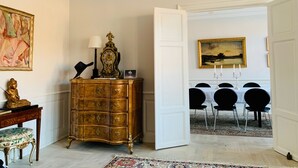 A room with a wooden cabinet, a table with chairs, a painting, and a door leading to another room. - Best Stay Copenhagen - Nyhavn 8 (Copenhagen)