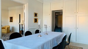A dining room with a long table, chairs, and a candelabra with candles. There are framed pictures on the wall and a chair in the corner. - Best Stay Copenhagen - Nyhavn 8 (Copenhagen)
