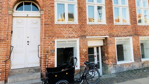 A red brick building with white doors and windows, a bicycle parked in front, and a sign above the entrance. - Best Stay Copenhagen - Nyhavn 8 (Copenhagen)
