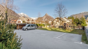 A parking lot with a van, houses, and mountains in the background. - Apartmaji Skok (Bovec)