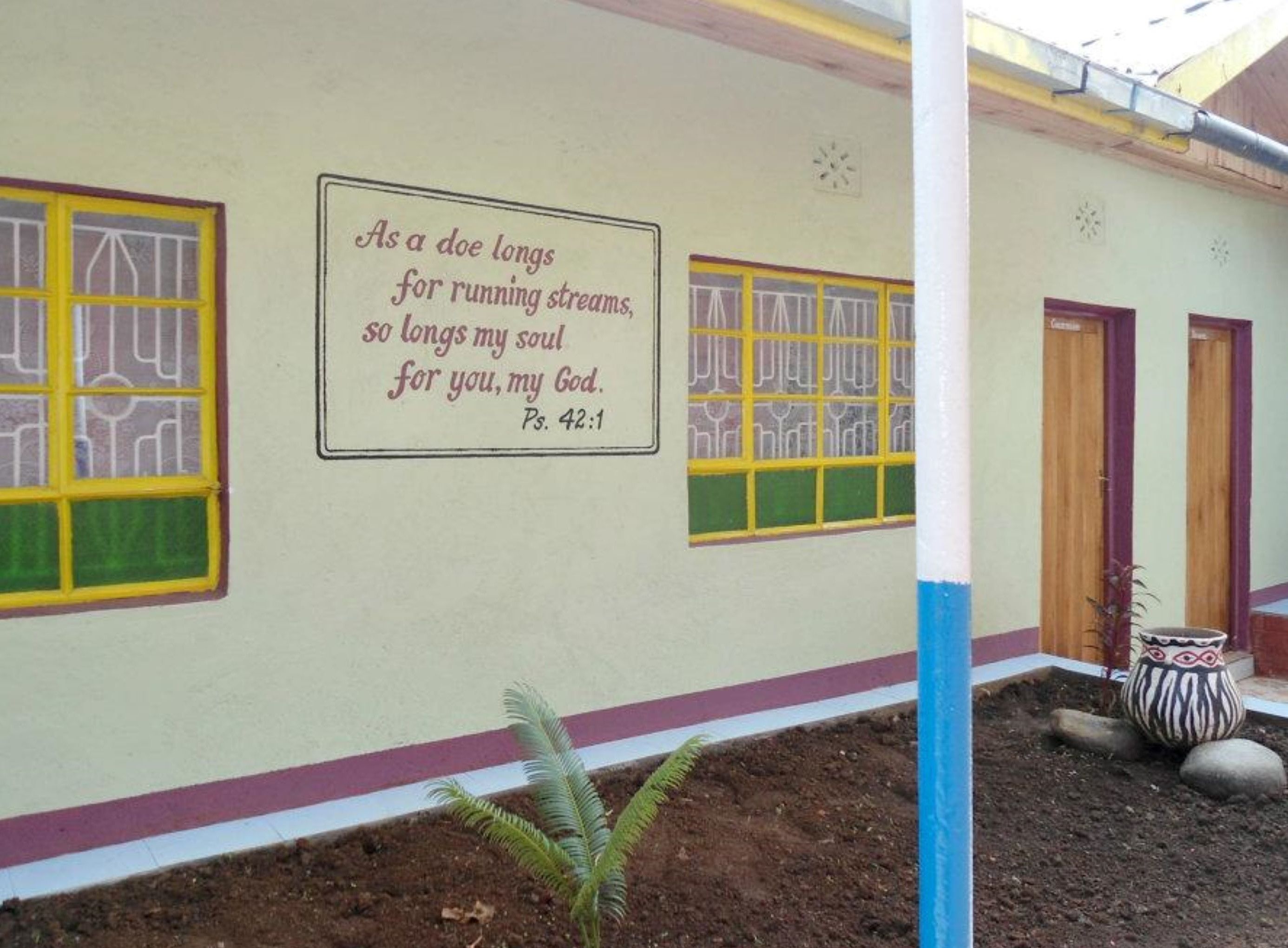 A building with a mural quoting Psalm 42:1. There are two doors and a window with yellow frames.