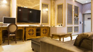 A hotel room with a large flat-screen TV, wooden furniture, and a sofa. - MYEONPUM DRIVE IN HOTEL (Jeongeup)