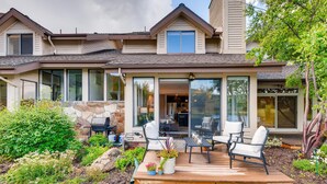 Une maison moderne dotée d’un patio aménagé avec du mobilier d’extérieur et un mur en pierre.