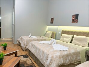 A hotel room with two beds, a wooden table, and a small plant.