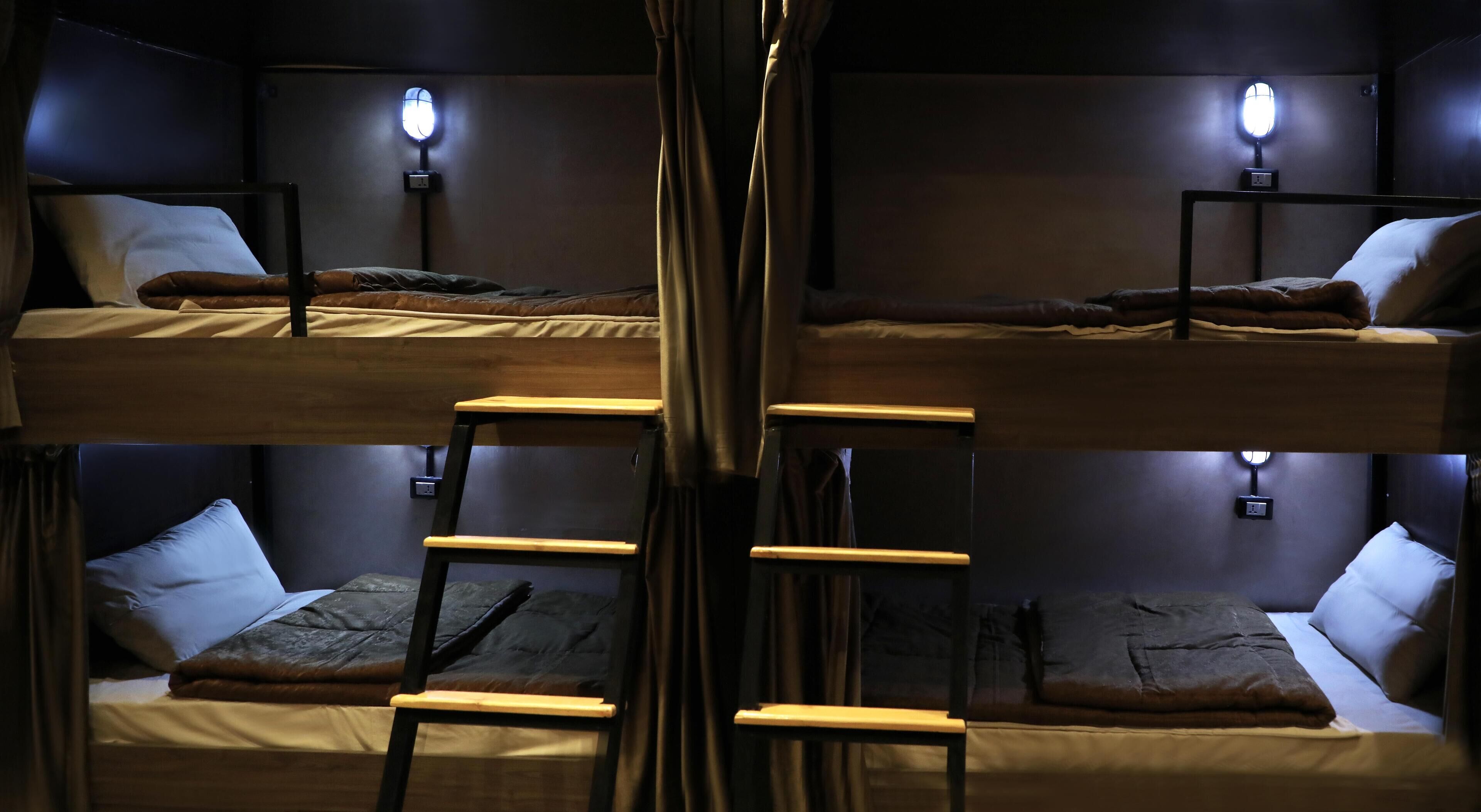 A bunk bed room with two bedside lamps, a ladder, and a small table.