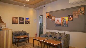 A lobby with a reception desk, two sofas, and a coffee table. There are wall art pieces depicting various subjects.