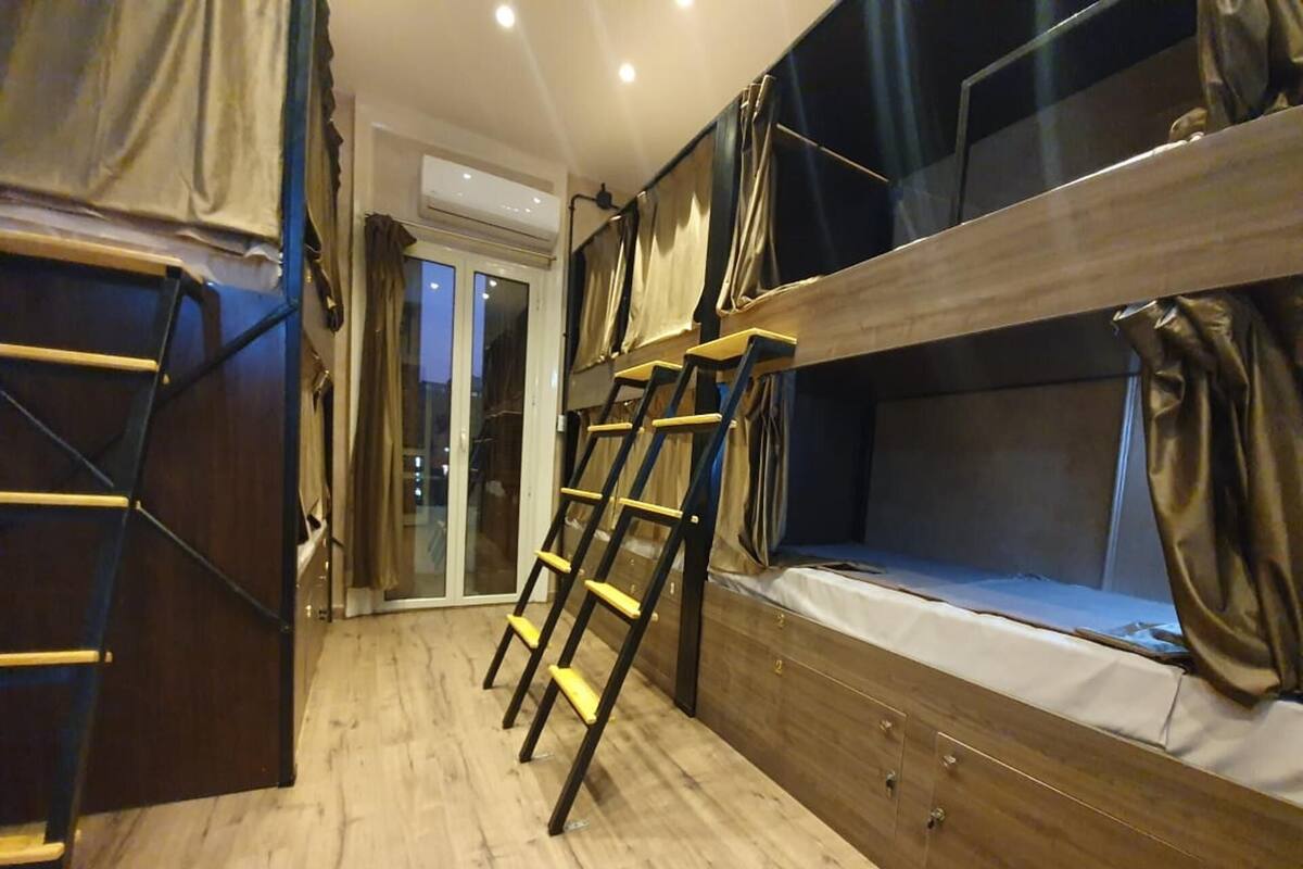 A bunk bed room with a ladder, wooden floor, and a sliding door.