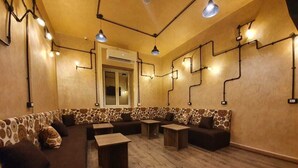 A cozy lounge area with patterned sofas, wooden tables, and pendant lighting. - Holy Sheet Hostel (Cairo)