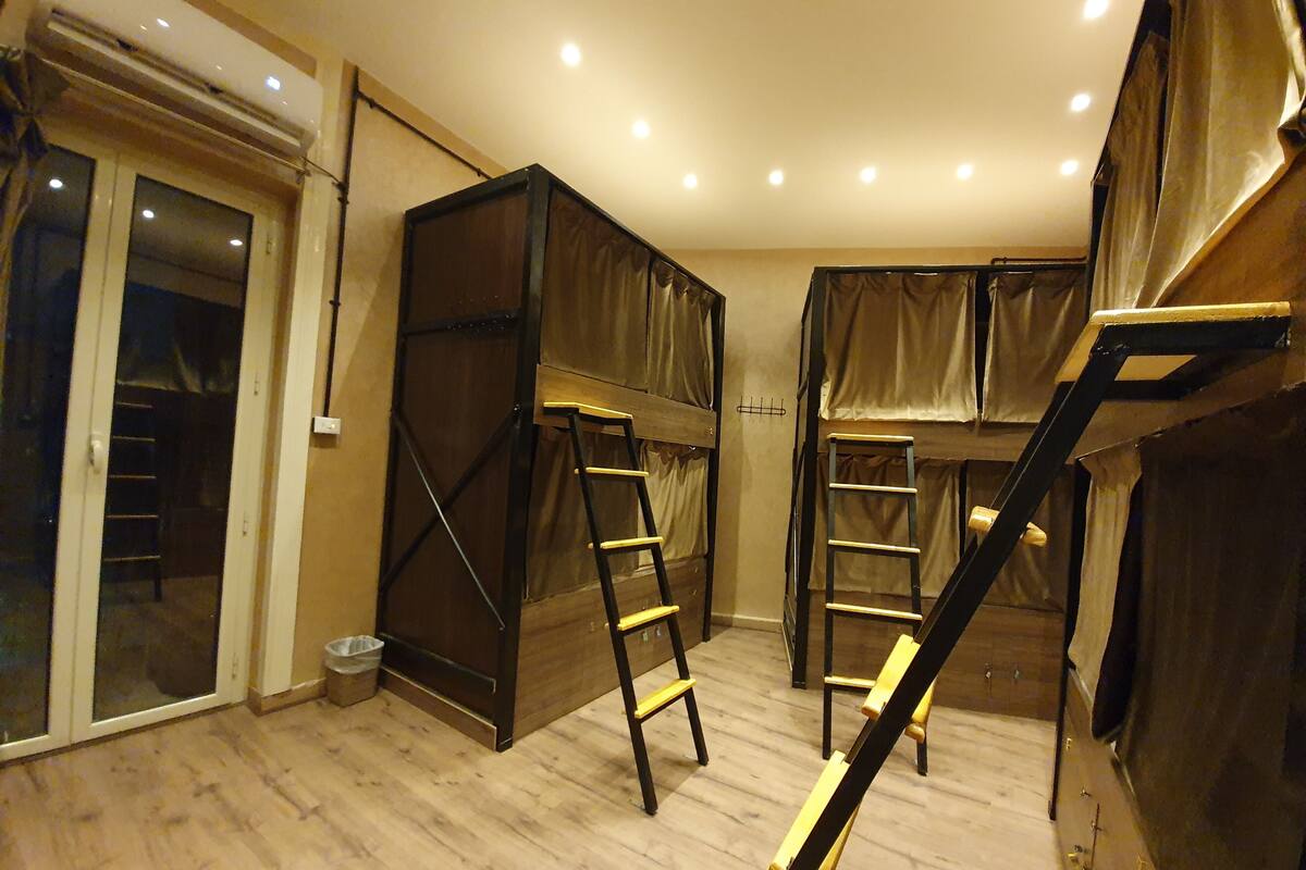 A room with bunk beds, wooden ladders, and a sliding glass door.