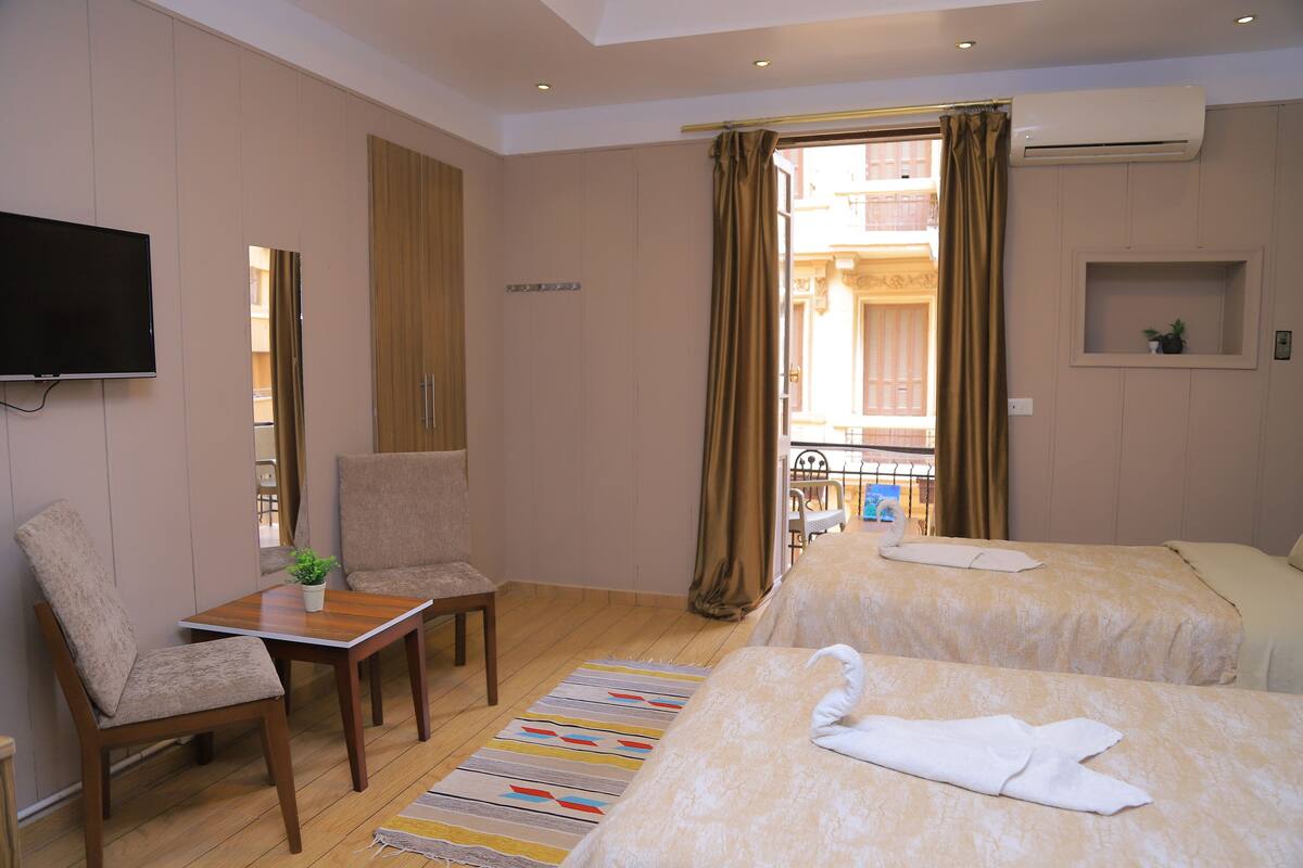 A hotel room with two beds, a TV, a desk, and a chair.