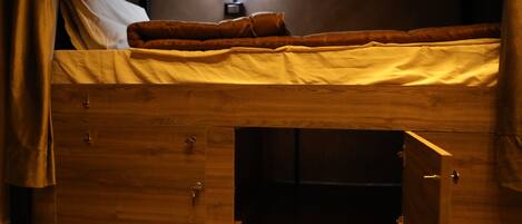 A bunk bed with a wooden frame, a pull-out drawer, and a bedside table.