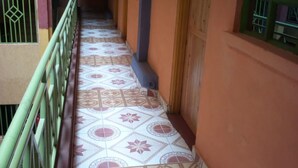 A corridor with patterned floor tiles, green railings, and wooden doors. - Bongo Restaurant & Hotel (Nairobi)