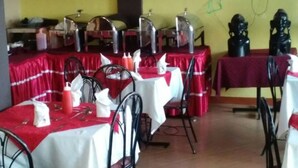 A dining area with tables set for service, featuring metal chairs and tables covered with red and white tablecloths. - Bongo Restaurant & Hotel (Nairobi)