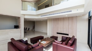 A spacious living area with a high ceiling, a seating arrangement, and a staircase leading to an upper level. - Ai Mei Homestay (Huxi)