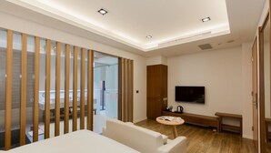 A modern hotel room with a large bed, a TV, a small round table, and a wooden partition separating the room from the bathroom. - Ai Mei Homestay (Huxi)