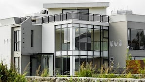 A modern multi-story building with large windows, a balcony, and a stone retaining wall. - Ai Mei Homestay (Huxi)