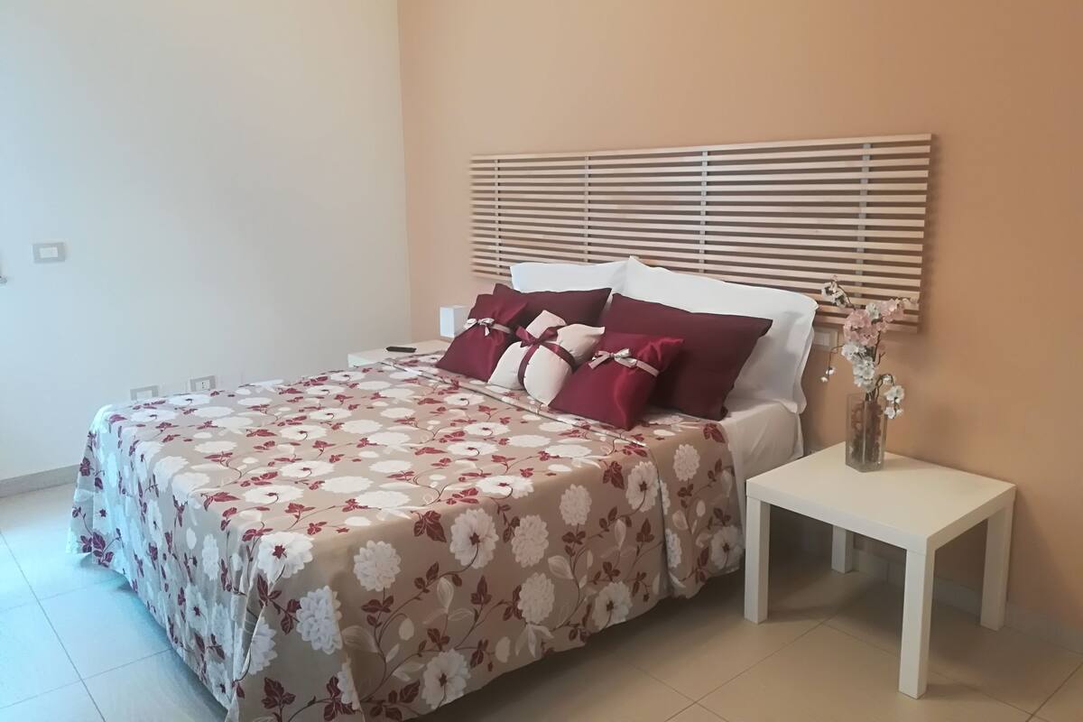 Un dormitorio con cama, mesita de noche y velador.