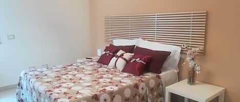 A bedroom with a bed, a bedside table, and a nightstand.