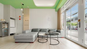 A modern living room with a sectional sofa, a round coffee table, and a kitchen area with a refrigerator. - Bo Ya Homestay (Liuqiu)