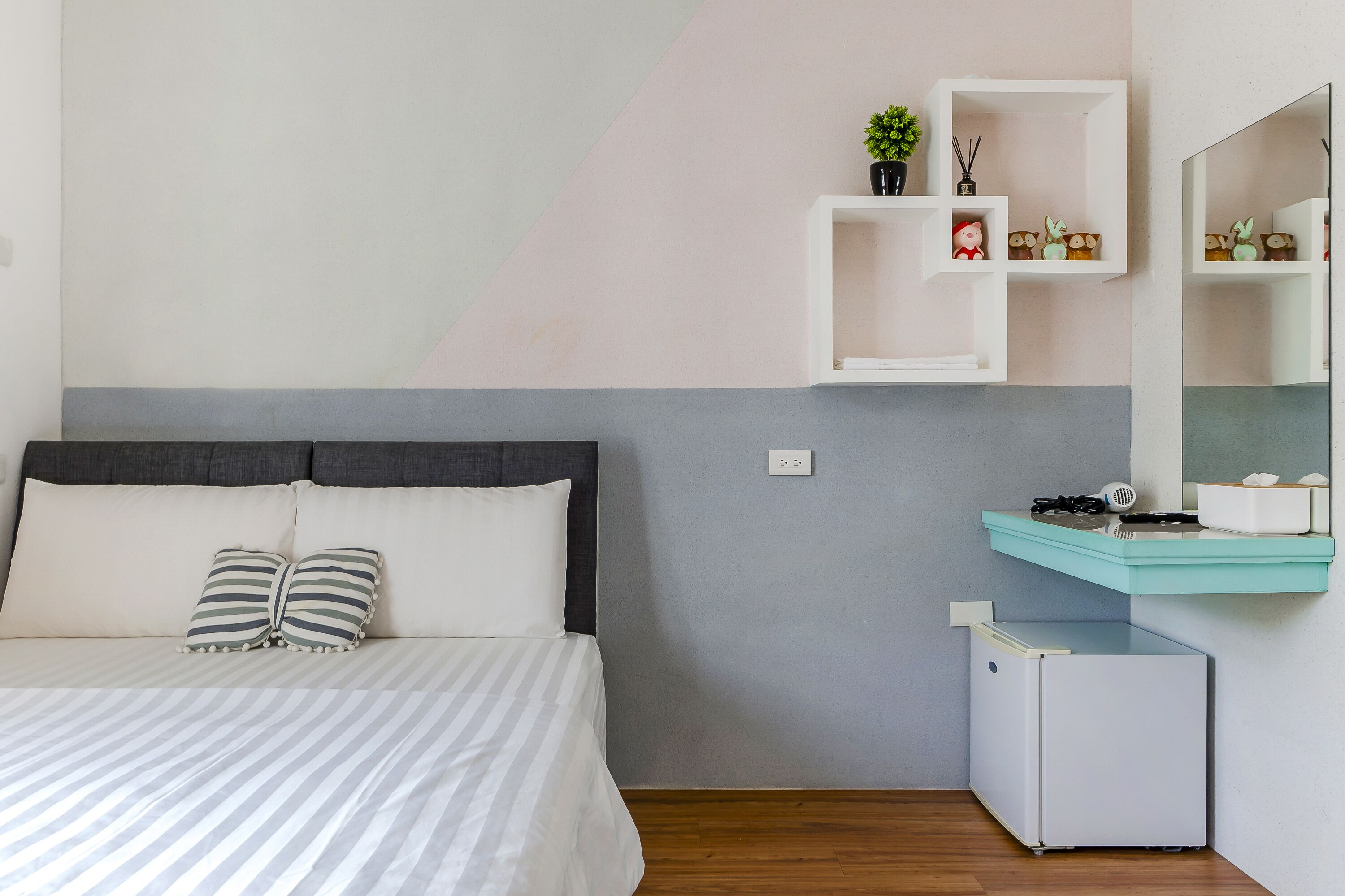 A bedroom with a bed, a nightstand, a small white cabinet, and a mirror.