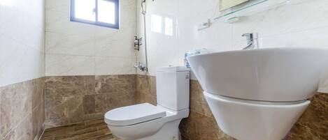 A bathroom with a toilet, a large sink, and a shower.