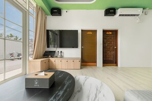 Habitación de hotel moderna con un gran ventanal, un armario de madera, una mesita de mármol y una puerta con un cartel.