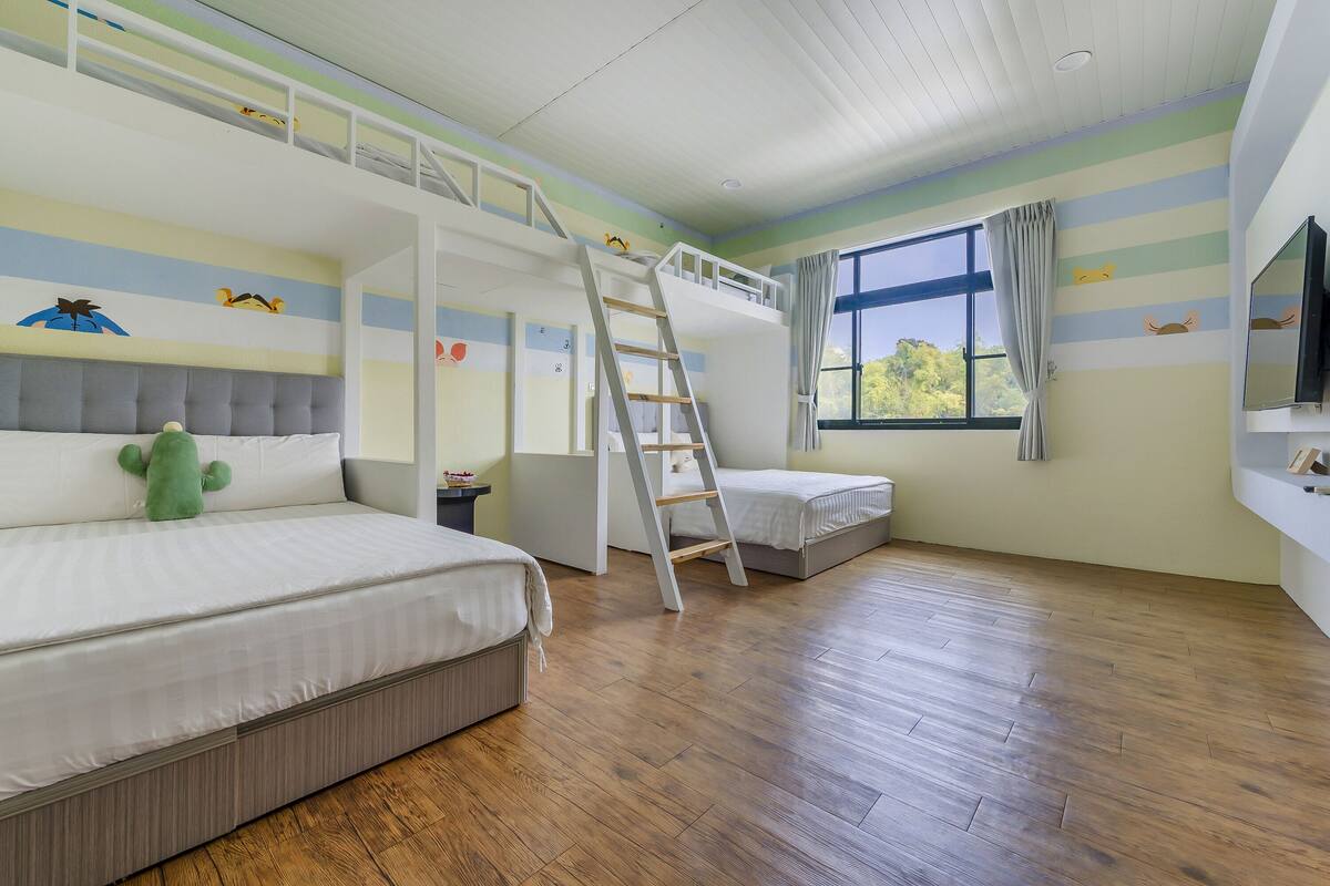Quarto com uma cama de solteiro, escrivaninha e janela com cortinas.