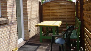 Un patio techado con una mesa y sillas, cerca de madera y pared de ladrillo.
