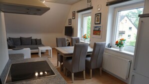 Una cocina moderna con comedor, estufa integrada y ventana con vista a una casa.