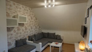 Una sala de estar moderna con un sofá seccional gris, una mesa de centro blanca y una pared con diseño.